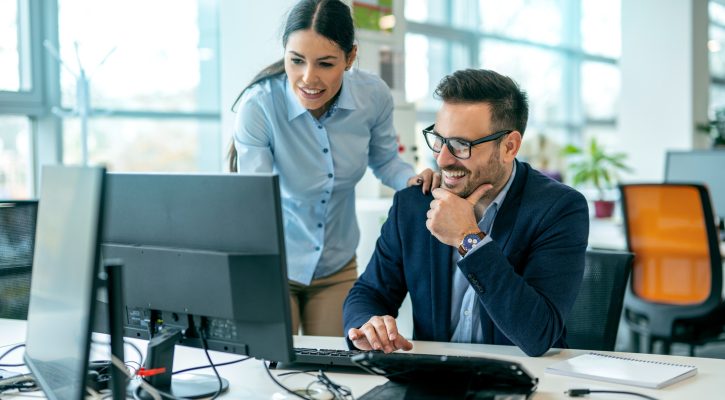 Male boss discussing online project with employee in the office